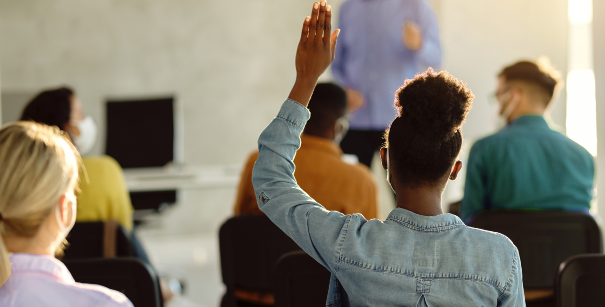 Person raising hand in classroom.