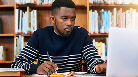 Law student studying at laptop in library.