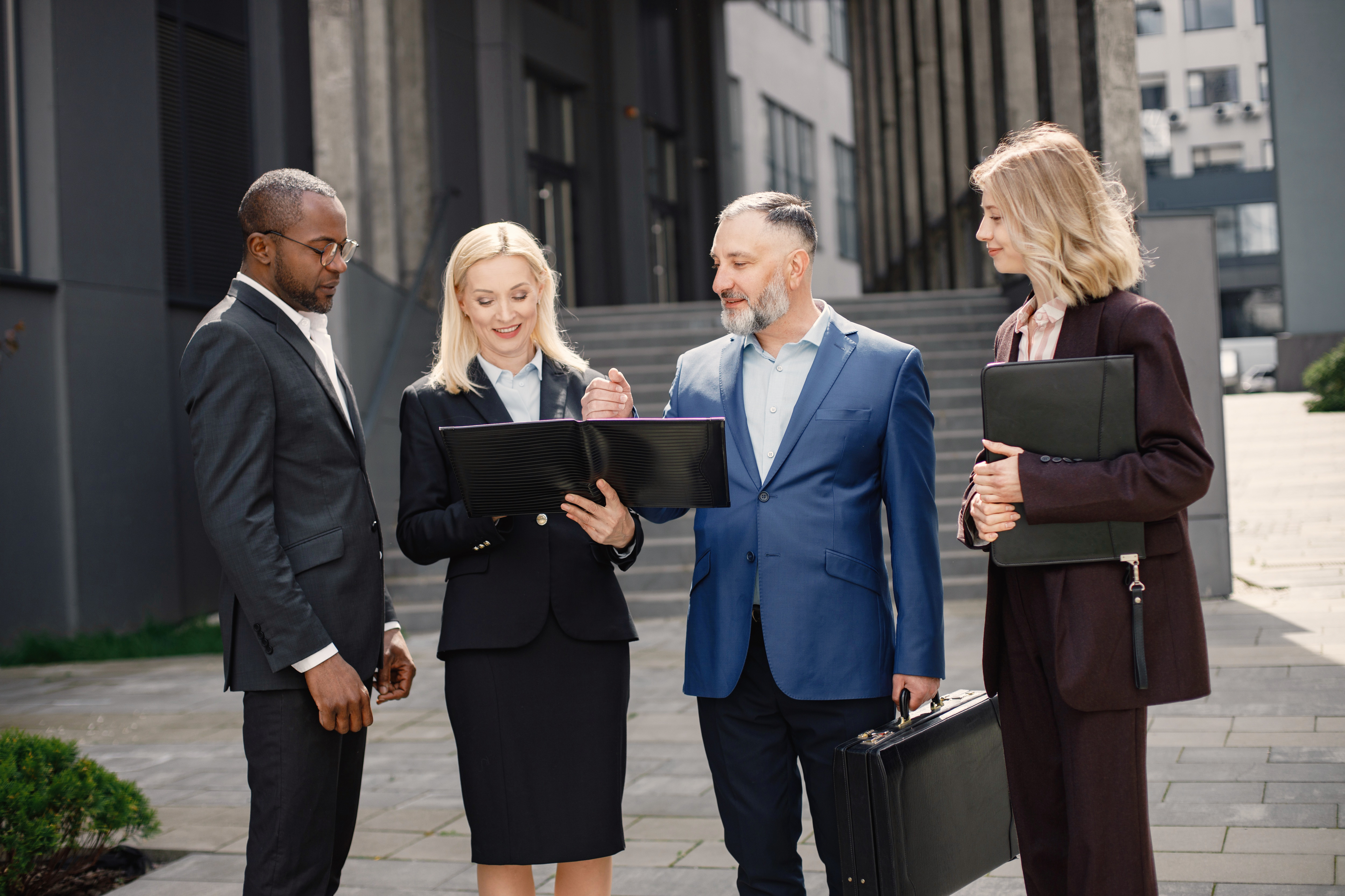 Group of legal professionals conversing on sidewalk outside of building