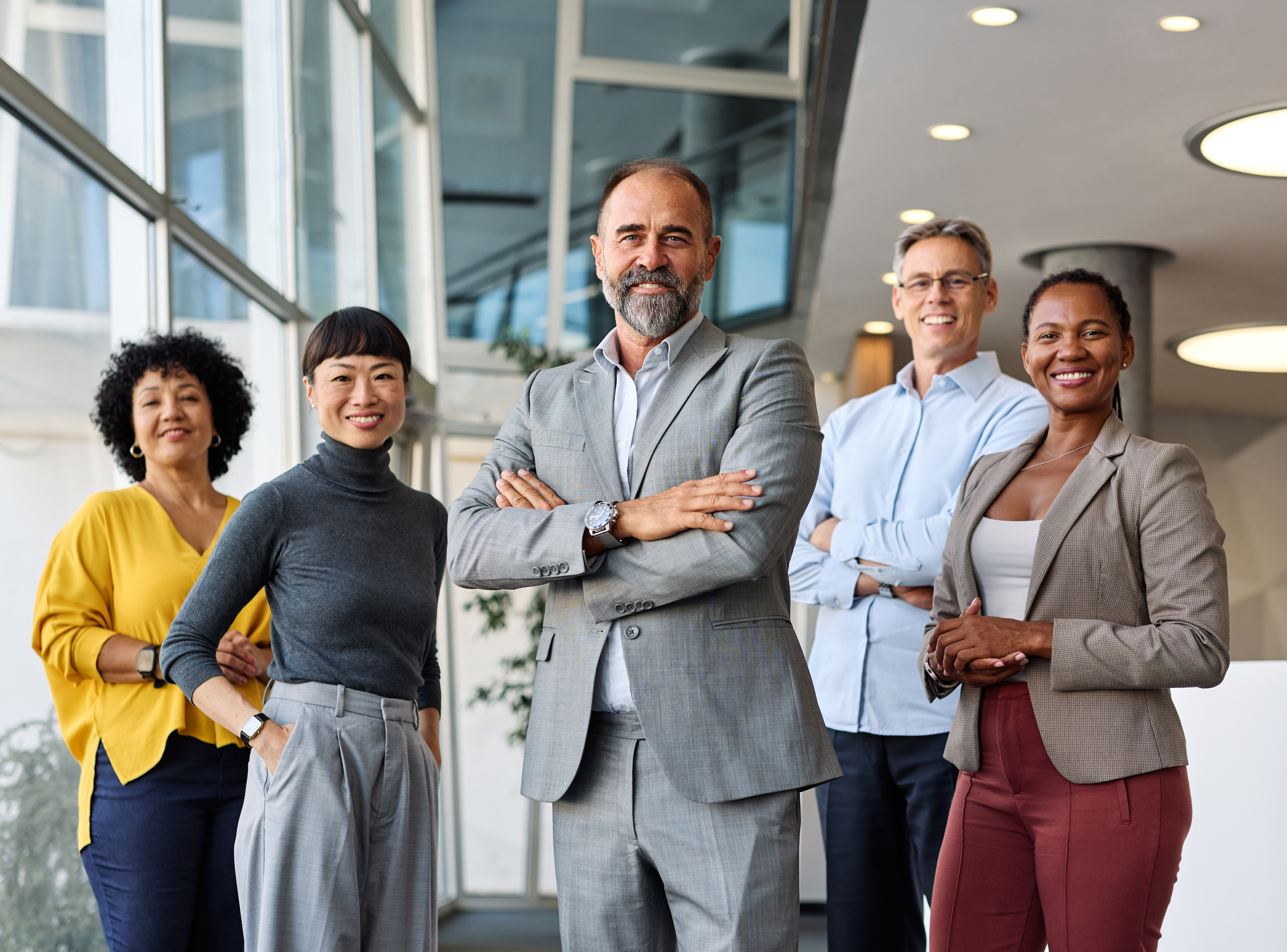 Group of legal professionals gathered inside modern office building smiling at the camera