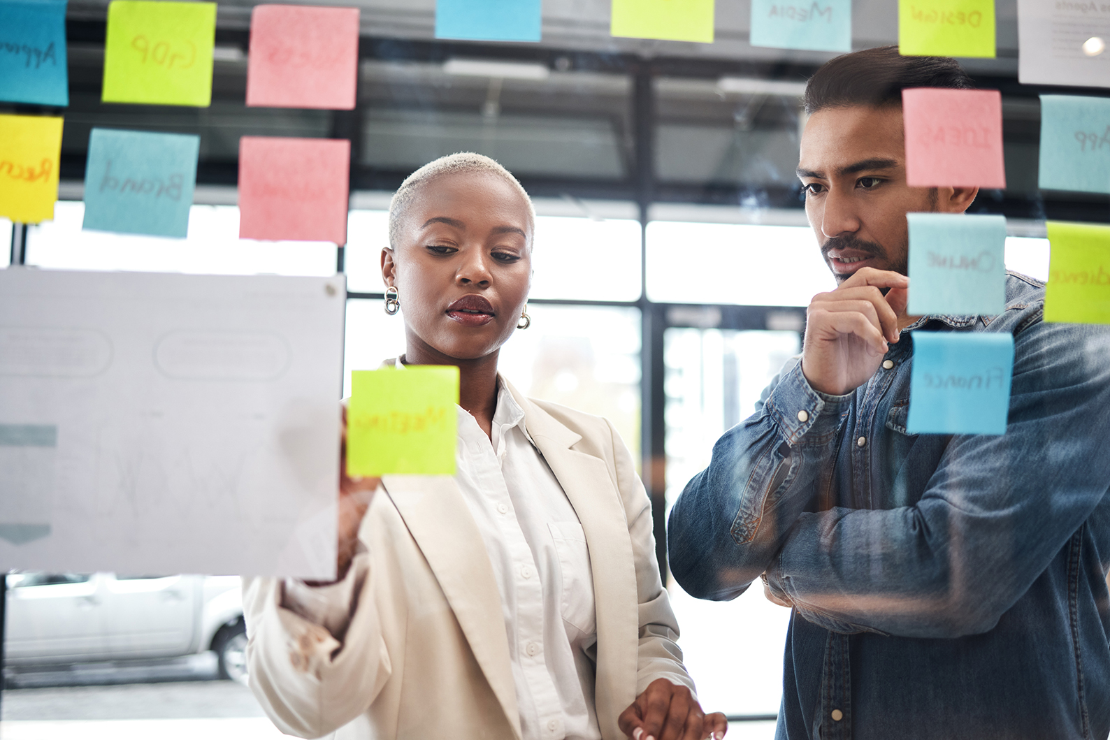 Two legal professionals reviewing post-it notes on window