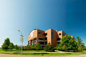 College of law exterior. Deciduous and evergreen trees surround the modern building.