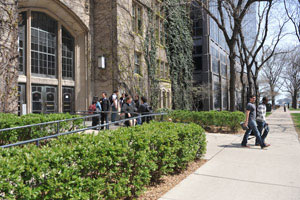 Students leave the School of Law. Green shrubs line the ramps and paths that lead to the building's entrance.