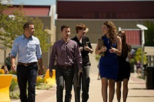 Students in button-down shirts or dresses walk down a path in groups, conversing.