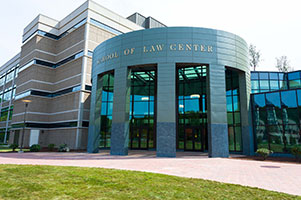 Law school exterior. A round vestibule with large windows reads, 'School of Law Center.'