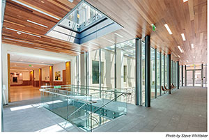 Photo by Steve Whittaker. Hallway inside Berkeley Law building. Glass walls. Wooden roof. Tile floor. Skylight over stairwell.