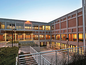 Law school exterior. A three-floor building with windons lining many of the walls. An outdoor staircase navigates between floors one and two.