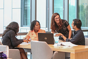 Diverse students work together at a library study table.