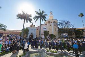 Graduates walk out of the College of Law as a crowd of people clap for them.