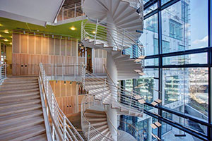 A white spiral staircase winds beside a wall made of windows.