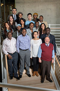 A diverse group of students pose with a professor.