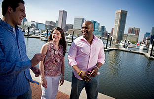 Three diverse students walk together, chatting along Inner Harbor.