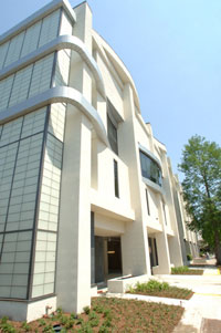 Law school exterior—a tall white building. Deciduous trees are in view.