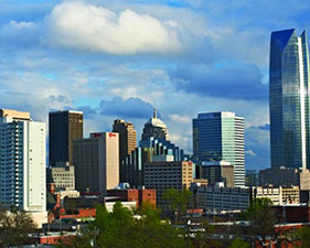 The skyscrapers of Oklahoma City stand tall beneath a cloudy, blue sky.