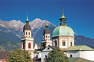 Domed buildings stand in front of a mountain range.