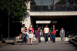 Diverse students walk down a broad path, away from the law school, in groups. Many hold books in their hands.