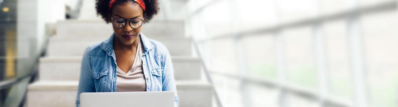 Female student on steps with laptop.