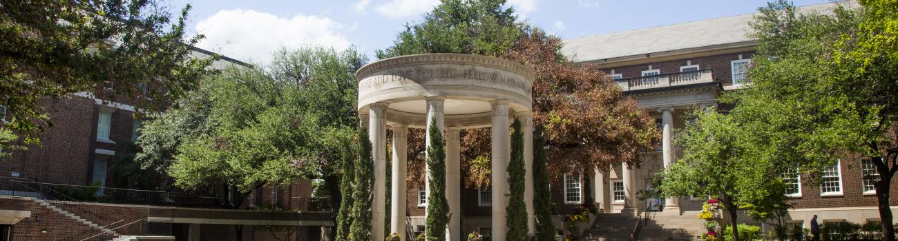a view of the SMU Dedman School of Law quad from the southeast. The tempietto is in the middle of the screen, decorated with florals for graduation and the Underwood Law Library is behind it to the left of the image and Storey Hall is behind the tempietto to the right of the image.