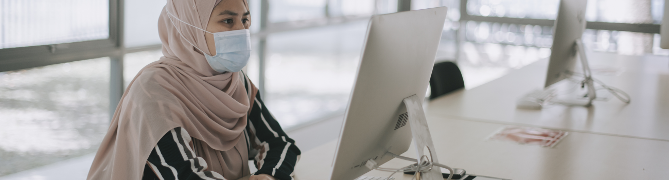 law school candidate wears a COVID-19 face mask as she researches law schools on a computer