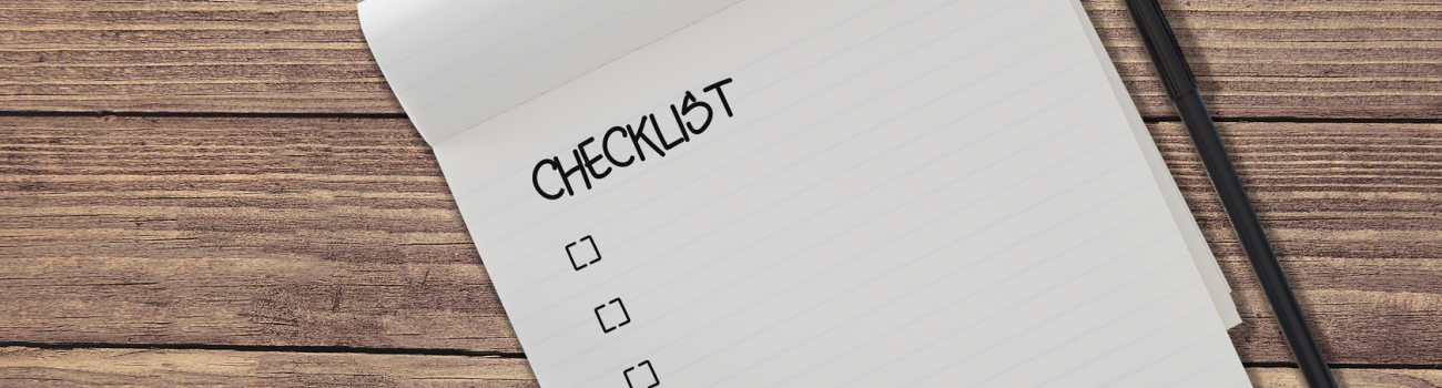 Checklist on pad with pen on wooden table