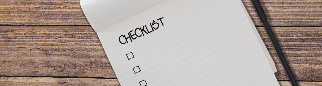 Checklist on pad with pen on wooden table