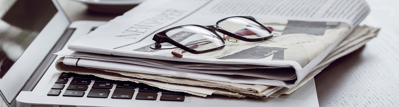 Laptop with newspaper and reading glasses