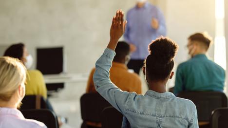 a student raising her hand in a classroom setting