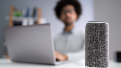 Person at desk with laptop and Amazon Echo device.