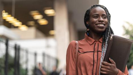 Law student smiling with books held in arm