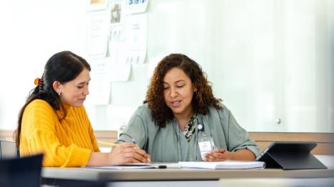 two people at desk going over notes