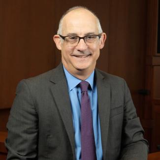 A man wearing a suit smiles at the camera