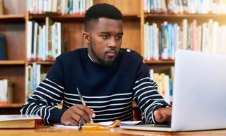 Law student at table in library using a laptop