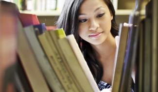 person looking through library bookshelf