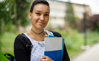 Law student smiling at camera with books in hand