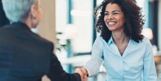 Law student smiling and shaking hands with law school admissions representative