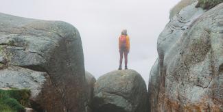 Person standing on large rock held between two precipices