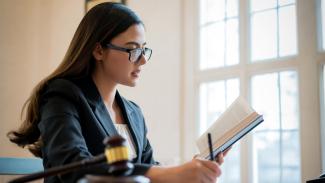 Person reading law textbook at table with gavel
