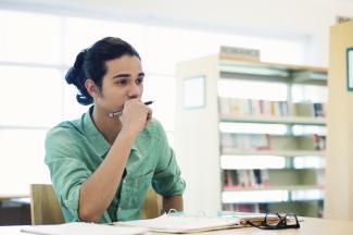 person seated at a desk, holding a pencil