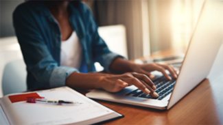 Close-up of person's hands typing on laptop