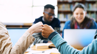 Students fistbumping at table