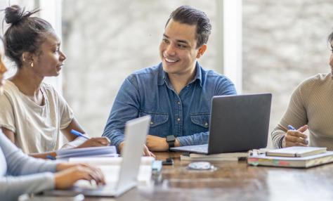 People with laptops sitting at a conference table. 