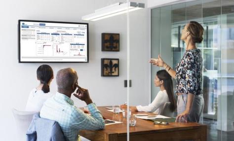People in a meeting room looking at a projected screen together. 