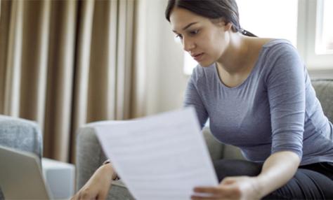 Woman with a sheet of paper and a laptop. 