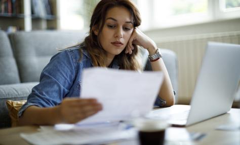 A woman looks at papers with a concerned look on her face