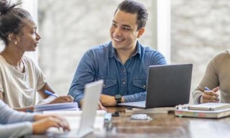 Man and woman talking to one another at a large table. They appear to be part of a group. 