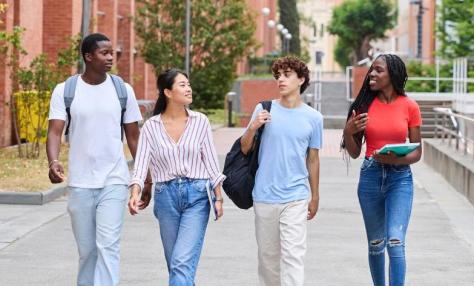 Four young people who appear to be students walking on campus. 