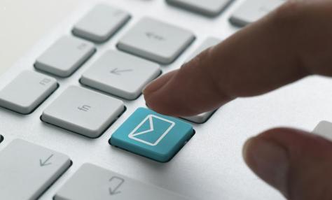A keyboard with a finger preparing to press what looks like an email "send" key. 