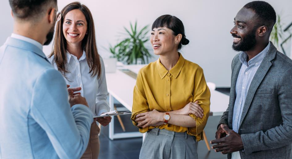 A group of people wearing professional clothing stand together, having a conversation