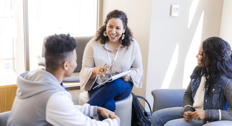 A teacher sits in a circle with two students