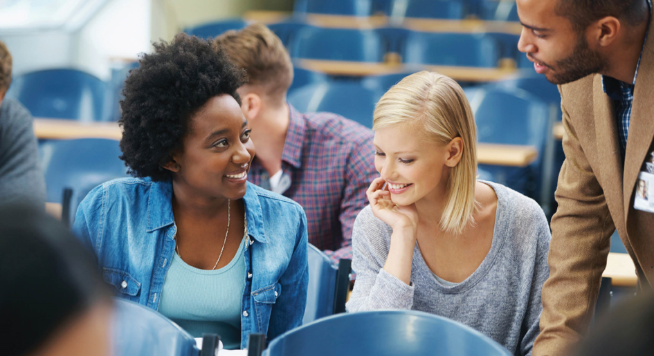 student speaks with a professor in a classroom settings